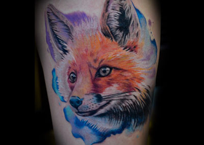 A colorful fox tattoo on the arm of a person.