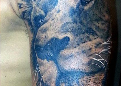 A close up of the face of a lion tattoo