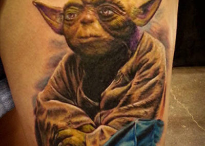 A tattoo of yoda sitting on the side of his body.