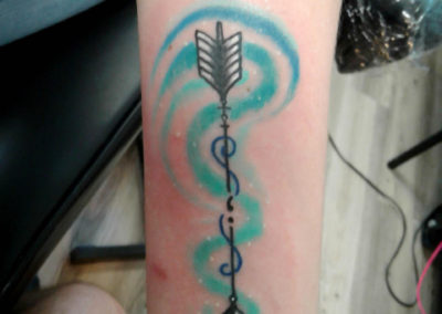 A tattoo of an arrow with a spiral design.