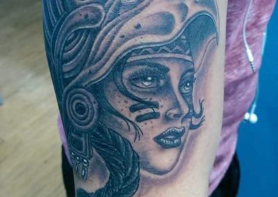 A woman 's face with an elaborate head dress on her arm.