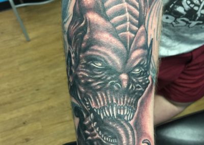 A tattoo of an evil looking demon on the arm.