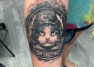 A cat wearing an astronaut helmet tattoo.