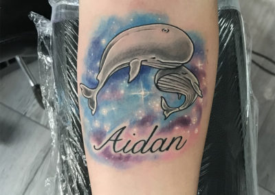 A whale tattoo with the name aidan on it.