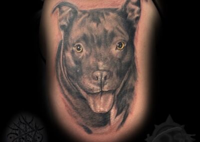 A black and grey tattoo of a dog 's face