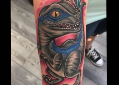 A tattoo of a lizard with blue eyes and a branch.