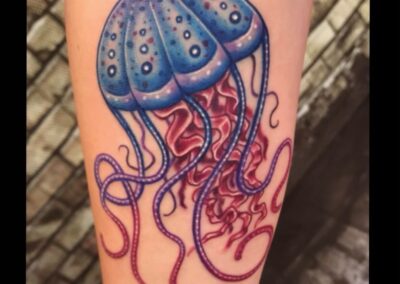 A blue and red jellyfish tattoo on the arm.