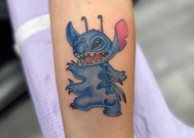 A tattoo of stitch is shown on the arm.