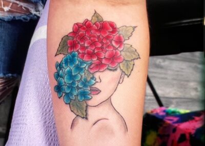 A woman 's face with two flowers on her arm.
