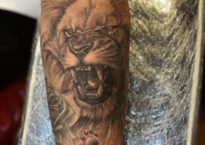 A tattoo of a lion 's head with paw prints on it.