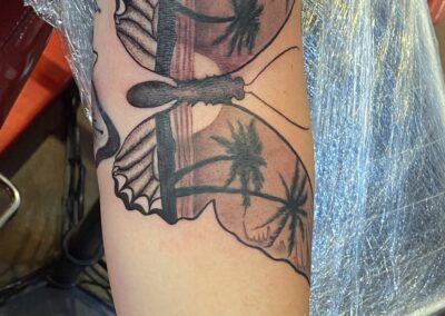 A butterfly tattoo with palm trees on it